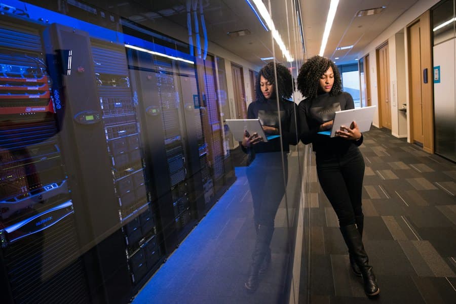 An engineer checking a tablet beside running servers